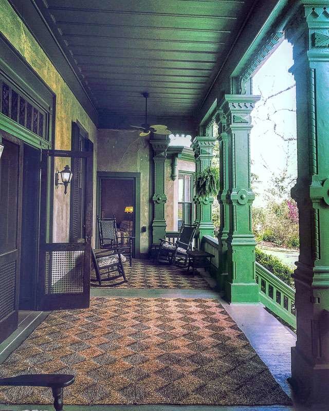 Southern Style front porch with green painted columns, screen door and architectural details